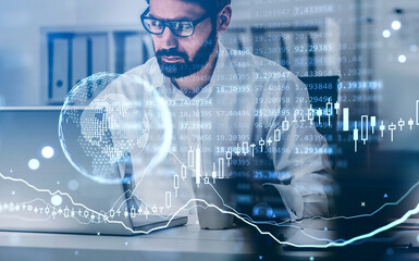 Businessman in eyeglasses with laptop, earth globe and candlesticks