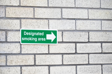 Designated smoking area direction arrow sign on wall