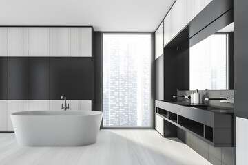 Naklejka na ściany i meble Modern design bathroom interior with white oval bathtub, black double sink, mirror, countertop, silver faucets. Panoramic window with skyscrapers city view. Wooden and grey tile walls.