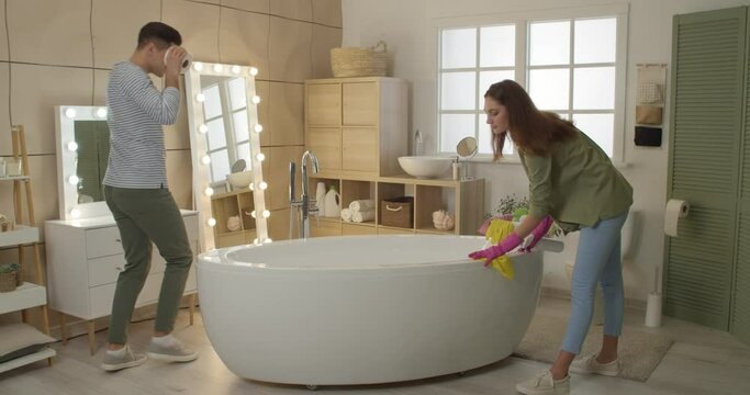 Young couple having fun while cleaning bathroom