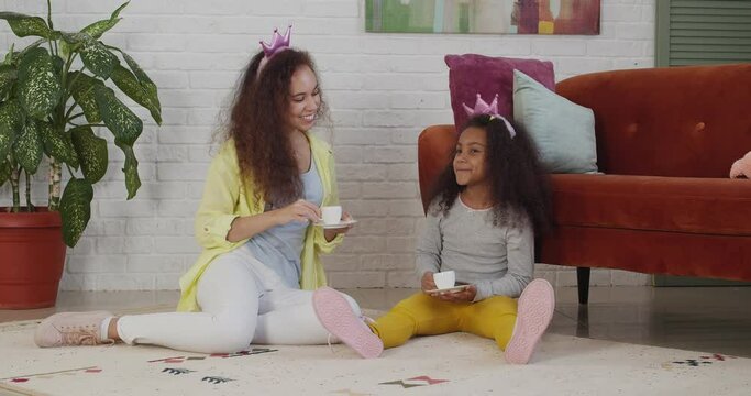 Young African-American woman and her little daughter playing at home