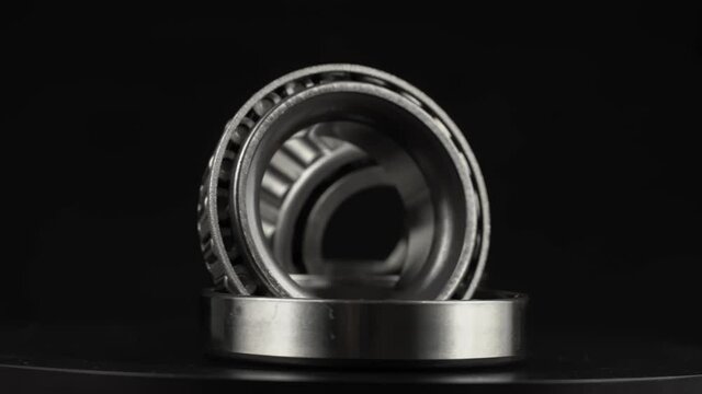 Cyclic seamless video with bearings rotating on a turntable on a black background. The two bearings rotate around their axis. Mechanism concept and equipment. Close-up, macro.