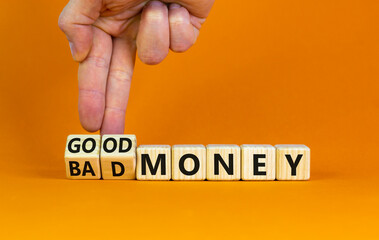 Good or bad money symbol. Businessman turns wooden cubes and changes words 'bad money' to 'good money'. Beautiful orange table, orange background, copy space. Business and good or bad money concept.