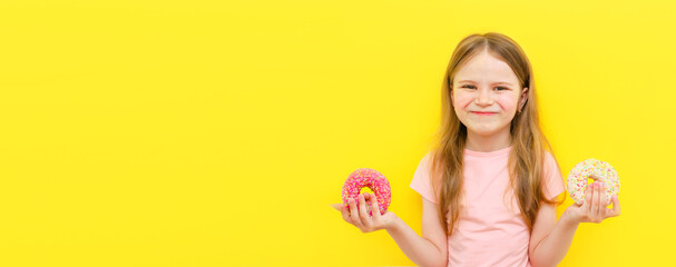 Fototapeta na wymiar World Donut Day or No diet day. A little girl holding donuts and smiling, holding on a yellow background. The concept. kids and doughnuts, sweets.
