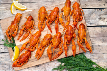 boiled crayfish on a wooden aged table and a wooden board with dill and lemon