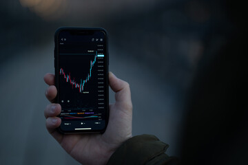 Male hand holding smartphone with real time forex chart on screen