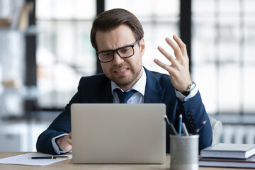 Concerned annoyed office employee upset about problems with laptop, not working service or online app, bad or lost connection. Worried nervous businessman feeling stress at workplace in office