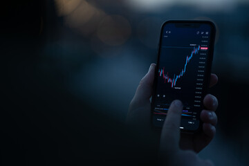 Investor checking stock exchange market data in mobile app on smartphone