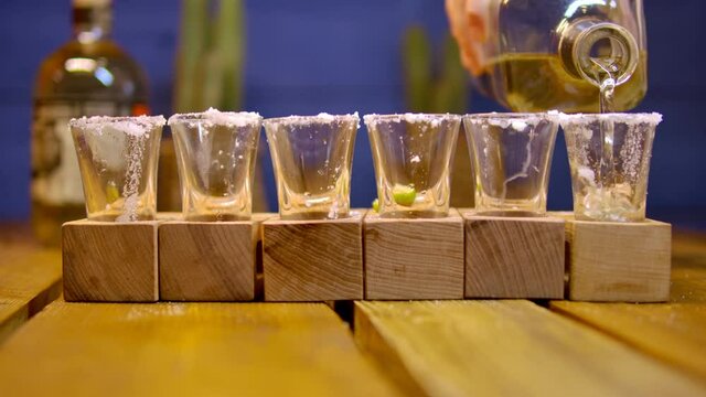 Traditional drink from Mexico tequila.  The bartender's hand pours cold tequila from a bottle into a shot. Party time. Time to drink