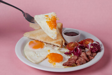 the girl cuts an omelet with a knife, breakfast in a plate, salad and egg, cucumbers and tomatoes