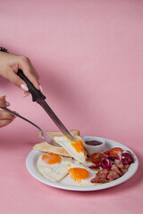 the girl cuts an omelet with a knife, breakfast in a plate, salad and egg, cucumbers and tomatoes