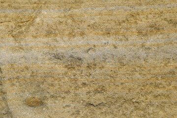 The texture of the uneven surface of the yellow sandstone stone with gray veins.