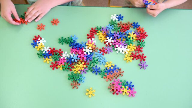 children play multicolored bright constructor on the table in kindergarten close-up. High quality 4k footage