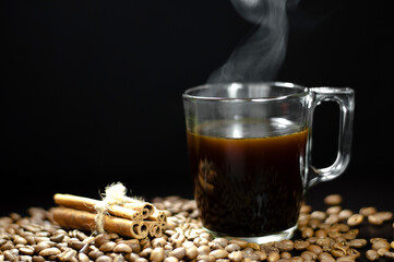 cup of coffee on a black table with grains and cinnamon