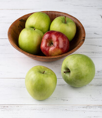 Green and red apples in a bowl over white wooden table