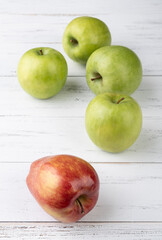 Green and red apples over white wooden table