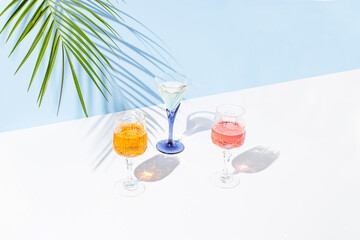 Creative summer composition with a fresh colorful cocktails, a glass and green palm branch. Summer, tropical, fresh cocktail concept.