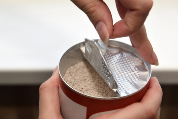Women's hands opening the lid of a jar of instant coffee with milk