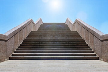 Wide stone staircase. Way up to blue sky in sunny day. Concept of hope and bright future. Freedom, career or success concept. Granite stairs.