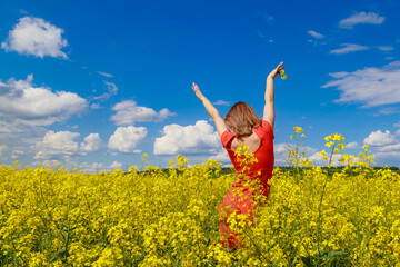 Young pretty woman in colored dress on Lightning cheerful yellow background blooming rapeseed...