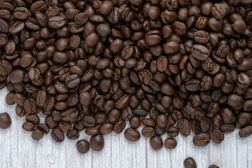 Roasted coffee beans on wooden floor background.