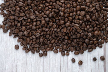 Roasted coffee beans on wooden floor background.