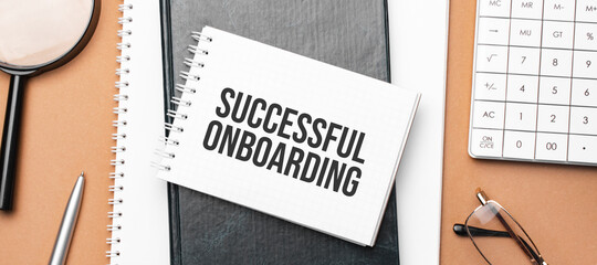 successful onboarding on notepad and various business papers on brown background. Brown glasses and...