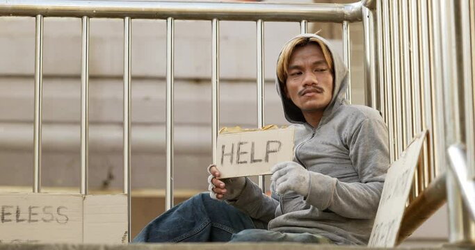 Homeless man sitting and holding help sign on the overpass