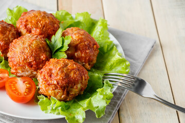 Homemade meat balls with vegetables in tomato sauce. Appetizing protein dish on a plate.
