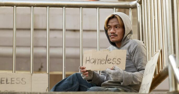 Homeless man sitting and holding homeless sign the overpass