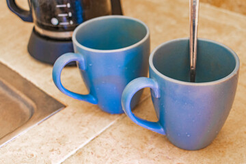 2 blue coffee cups and black coffee maker from Mexico.