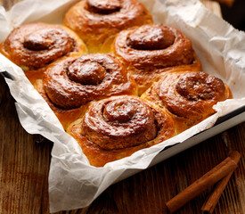 Traditional spiral-shaped cinnamon buns on a wooden table, close up view