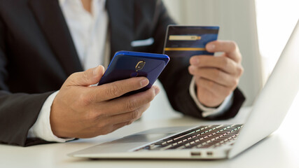 Young women hold credit cards and use laptop computers and mobile telephones to shop online, e-commerce, internet banking, spend money, work from home