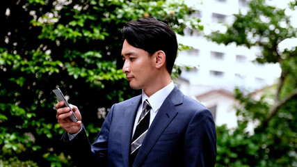 屋外でスマホを操作するビジネスマン