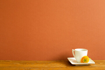 White coffee cup with yellow flower on wooden table. brown background