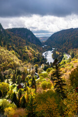 The forest of the Agawa Canyon in Ontario glistens in the sun after a storm has passed, with a river and lake in the distance.