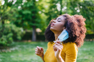 Pretty afro woman, relieved to remove her face mask.