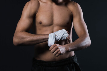 Naklejka premium Closeup male fighter hand with bandages. Fighter's fists clenched before a fight or training in a sports gym.