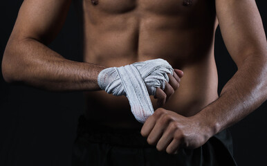 Closeup male fighter hand with bandages. Fighter's fists clenched before a fight or training in a sports gym.