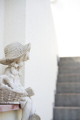 A sculpture of a girl sitting on a white wall bench and reading a book