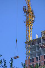 A construction crane lifts a load on a house under construction