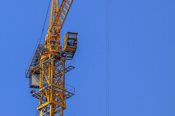 Fototapeta premium The top part of a working construction crane on a blue sky background