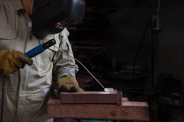 Fototapeta premium A welder is welding steel in an industrial factory. The welder wears protective clothing to work in the workplace.