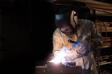 Fototapeta na wymiar A welder is welding steel in an industrial factory. The welder w