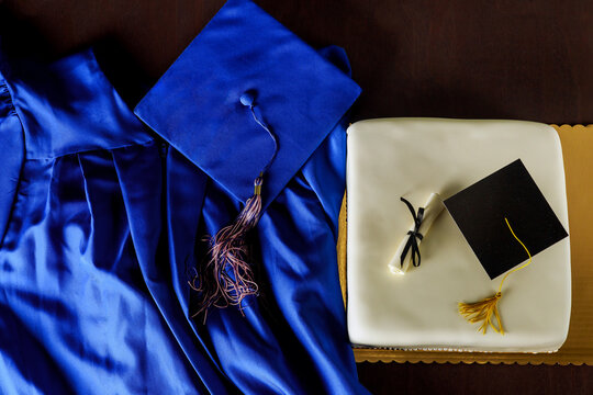 Top view of graduation blue hat and gown with cake.