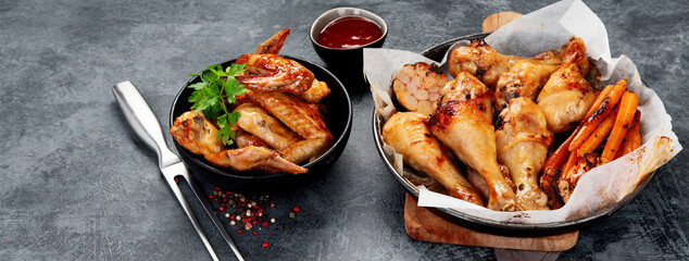 Roasted chicken legs with garlic and sauce on gray background.