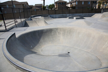 View of outdoor empty concrete skate park with ramps and pipes in California. Fun for all ages.