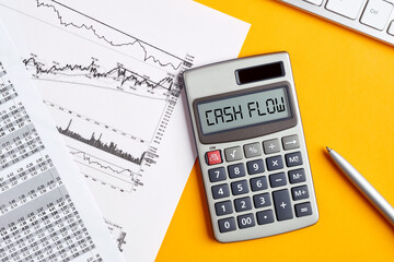 The word cash flow on calculator display screen with business office desktop. To calculate or analyze financial cash flow - obrazy, fototapety, plakaty