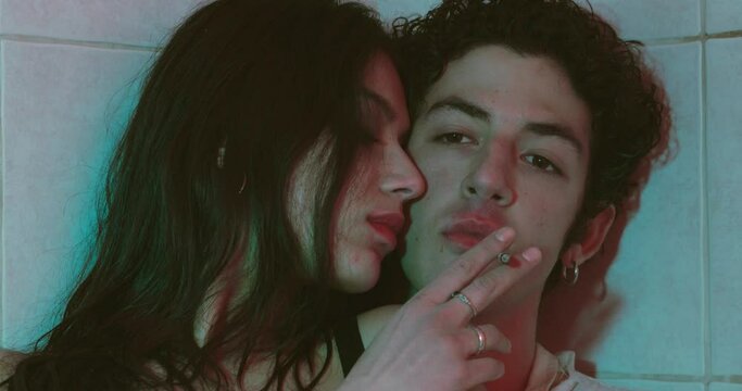 couple of junkies with stoned face passes each other a joint and kisses