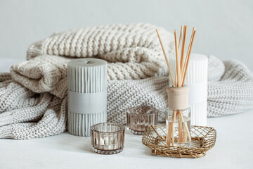 Cozy home composition with candles, aroma sticks and a knitted element.